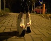 crossdresser walks on the street in latex leggings and very high white wedges from trans like a very thin girl